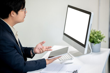 A male office worker is presenting work to a client on a computer in the office.