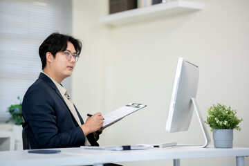 Male office worker checking documents on computer desk in office