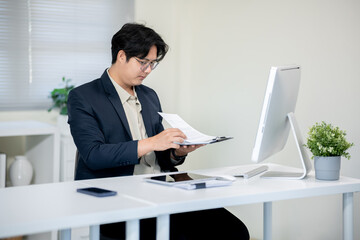Male office worker checking documents on computer desk in office