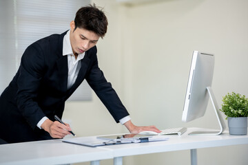 A businessman is discussing work with a client at a desk in an office.