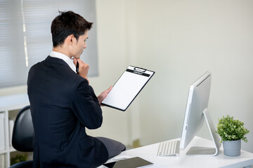 A businessman is discussing work with a client at a desk in an office.