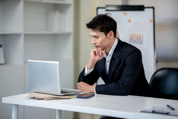 A businessman is discussing work with a client at a desk in an office.