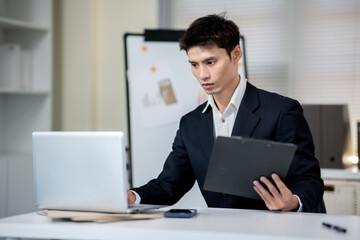 A businessman is discussing work with a client at a desk in an office.
