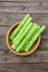 Fresh Green Celery Sticks in Wicker Basket on Rustic Wood Background