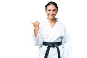 Young Uruguayan woman doing karate over isolated chroma key background pointing to the side to present a product