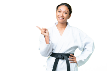 Young Uruguayan woman doing karate over isolated chroma key background pointing finger to the side