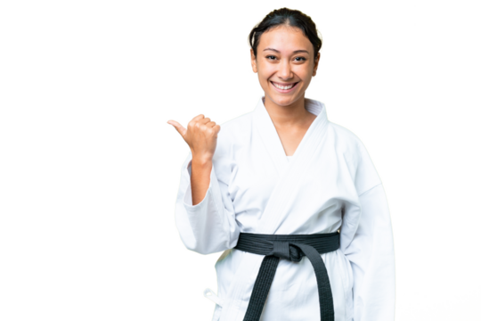 Young Uruguayan woman doing karate over isolated chroma key background pointing to the side to present a product - Powered by Adobe