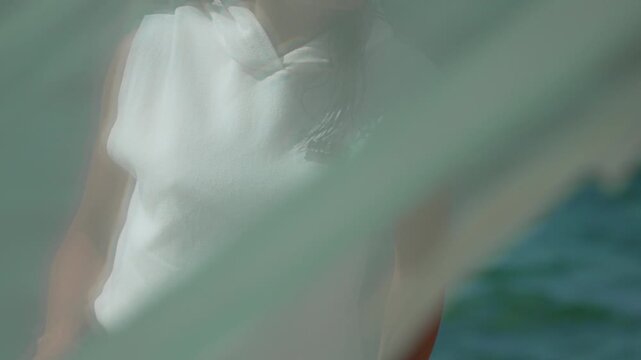 Sheer fabric, woman, beach, partially visible woman on sandy beach through flowing sheer fabric.