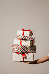 A person's hand holding a tower of stacked Christmas gifts with colorful ribbons