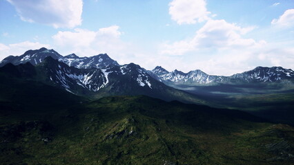 Breathtaking views of a rugged mountain range rise high above lush green valleys.