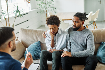 Father with his teenage son at meeting with social worker, psychologist discussing mental health...