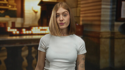 Young blonde woman with arms crossed in a candlelit gothic church hall stop gesture; denial rejection.