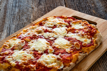 Pinsa Margherita with tomato sauce and mozzarella cheese on wooden background