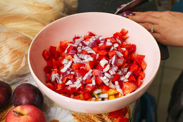 Fresh chopped salad with red pepper, onion, and cucumber in bowl. Homemade healthy food preparation in kitchen. Fresh vegetables ready for meal and cooking inspiration.