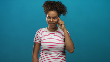 Woman finger to temple in studio with teal wall and striped t shirt, eyes closed in a thinking...