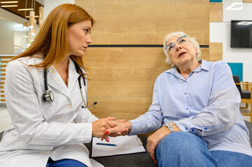 Obraz premium Female doctor consoling sad senior woman in hospital showing empathy and emotional support during medical consultation