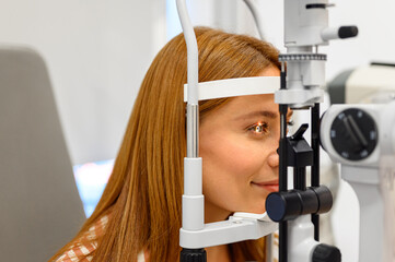 Close-up of female patient undergoing eye examination with slit lamp light focused on her eyeball...