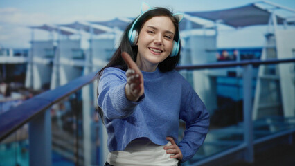Woman enjoying a cruise ship deck with headphones and a playful expression, showcasing a relaxed...