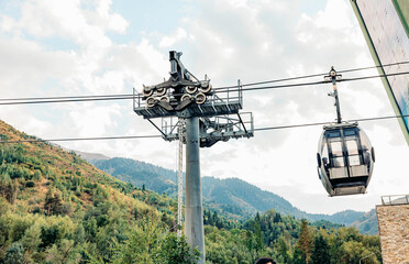 cable car station in the mountains. The structure is supported by a tall pole, surrounded by lush...