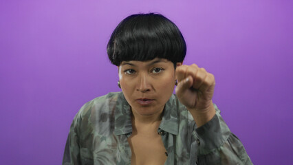 Woman gesturing with hand in front of isolated purple background conveying communication or...