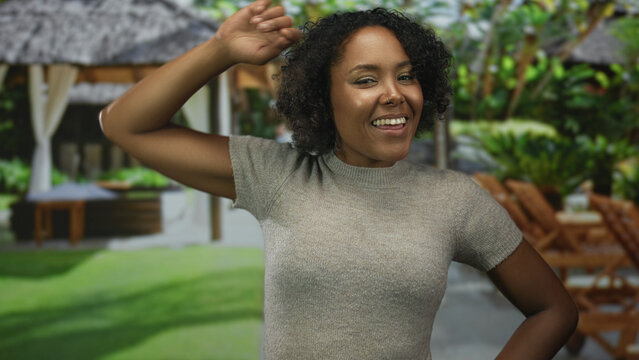 African american woman wipes sweat from forehead with hand inside hotel building poolside lounge; relaxation.