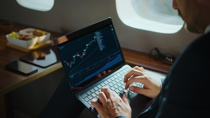 Unrecognized financial analyst working on a laptop, checking stock market charts and cryptocurrency rates, traveling in a luxury private jet. Over-the-shoulder view of a successful trader - Powered by Adobe