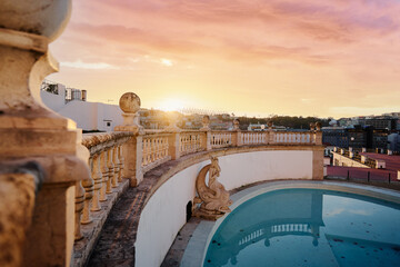 A park terrace with an empty pool and a cityscape view at sunset.