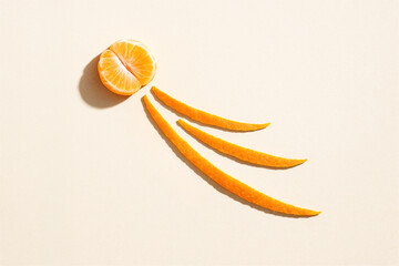 Tangerine fruit segment and three peels forming a comet or sun shape on a light background, representing christmas holiday, freshness, energy, and minimalist art with citrus