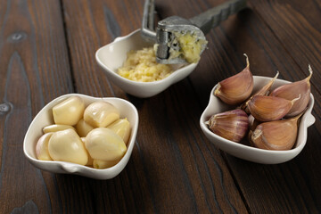 Fresh Garlic Cloves and Garlic Press on Rustic Wooden Table