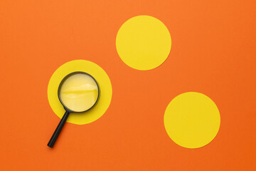 Creative Concept of a Magnifying Glass Overlapping Vibrant Yellow Circles on an Orange Background