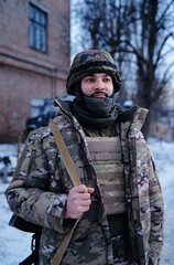 Naklejka premium Urban photo of Fully equipped desert camouflage soldier in mask, helmet, armor standing with rifle