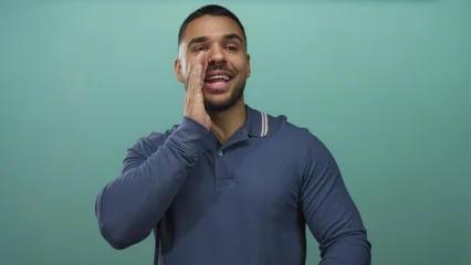 Selbstklebende Fototapeten Palme Young man beckons with hand at mouth while smiling in a vibrant studio  invitation connection welcoming.  © Krakenimages.com