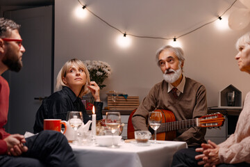 Family of friends enjoying an intimate gathering, enriched with music and meaningful conversation, in a warmly lit setting. A delightful evening emphasizing togetherness and artistic expression.
