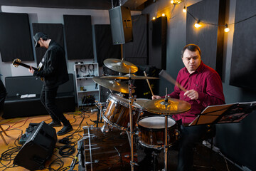 Musicians Rehearsing in a Studio with Drums and Guitar in Focus