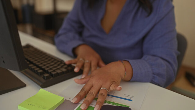 Woman points finger to computer screen above keyboard while working at desk in office; concentration. - Powered by Adobe