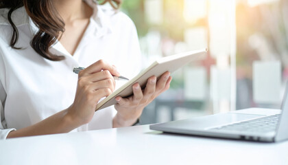 Woman writing notes planner agenda schedule productivity focus morning light, clean desk workspace minimal style with laptop and notebook inspiring calm mood