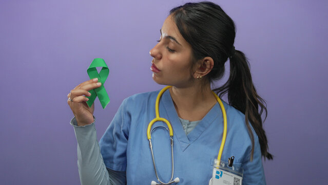 Doctor woman wearing uniform holds green ribbon over purple wall, symbolizing awareness. - Powered by Adobe