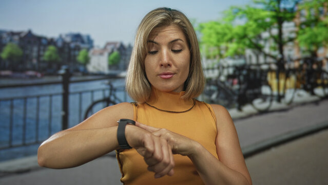 Blonde woman points finger to watch on wrist on street by a bike; urgency punctuality waiting time planning.