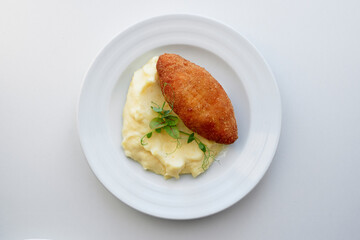 Smooth bed of mashed potatoes topped with golden fried croquette and sprig of microgreens, presented on a clean white plate. Warm, comforting, and restaurant-style, ideal for food photography.
