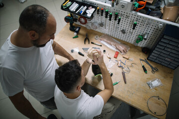 Two technicians collaborating on prosthetic arm in workshop