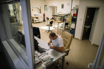 Man filling out paperwork at his desk in a workshop