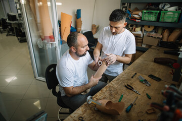 Two technicians collaborating on prosthetic arm in workshop