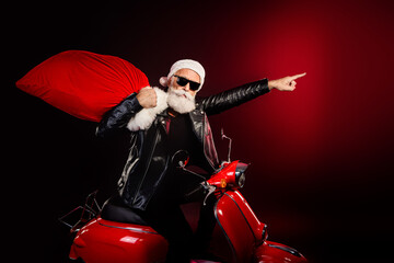 Santa rocker in red leather jacket on a motorcycle with a large bag celebrating christmas and...