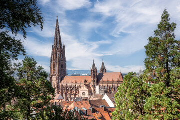 Panoramic view of Freiburg im Breisgau from a mountain viewpoint, featuring the historic Freiburg Minster and the cityscape under a clear blue sky.