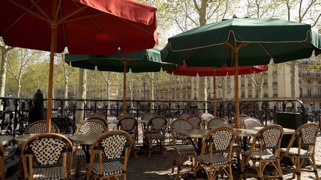 Outdoor cafe seating with green and red umbrellas in urban setting  