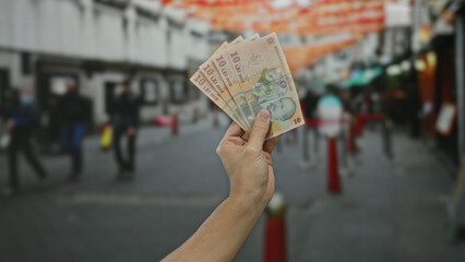 Man holding romanian lei banknotes in an urban street setting, showcasing pristine currency against...