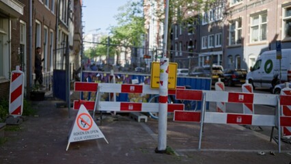 Urban construction site with blurred man behind barricades and warning signs indicating no smoking...