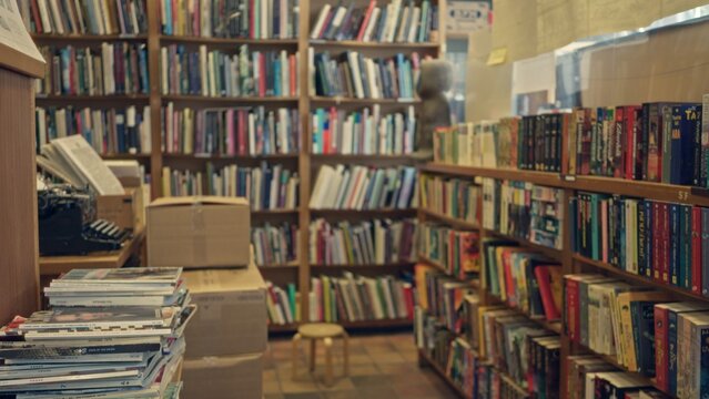 Library interior featuring shelves filled with books, magazines, and a blurred person in the background, creating a cozy and defocused reading environment. - Powered by Adobe