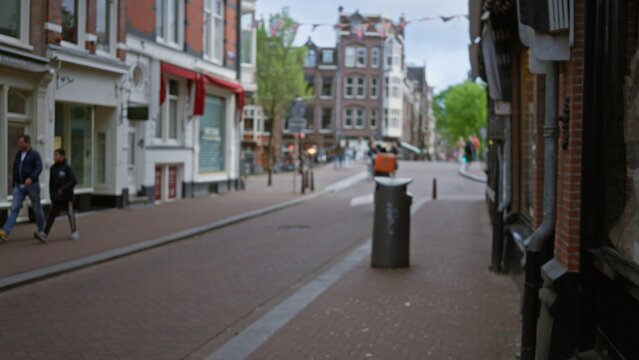 People walking along a blurred street in a european city featuring bokeh effects with classic architecture and a lively outdoor urban atmosphere.