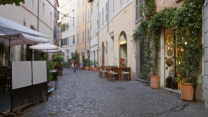 Rome cobblestone alley blurred with soft bokeh and defocused storefronts, planters and tables lining a narrow historic lane; background copyspace.